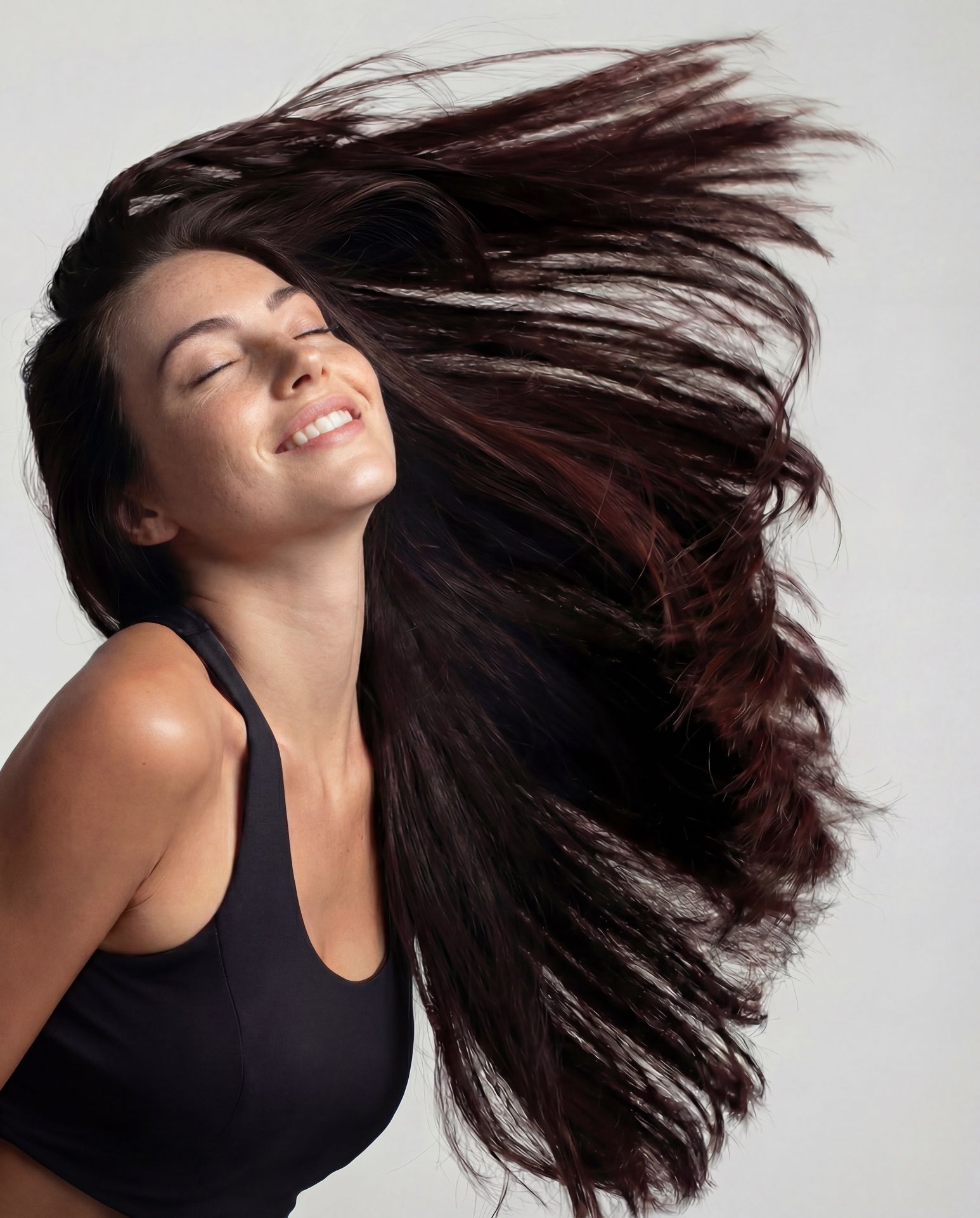 Woman tossing voluminous dark hair, smiling